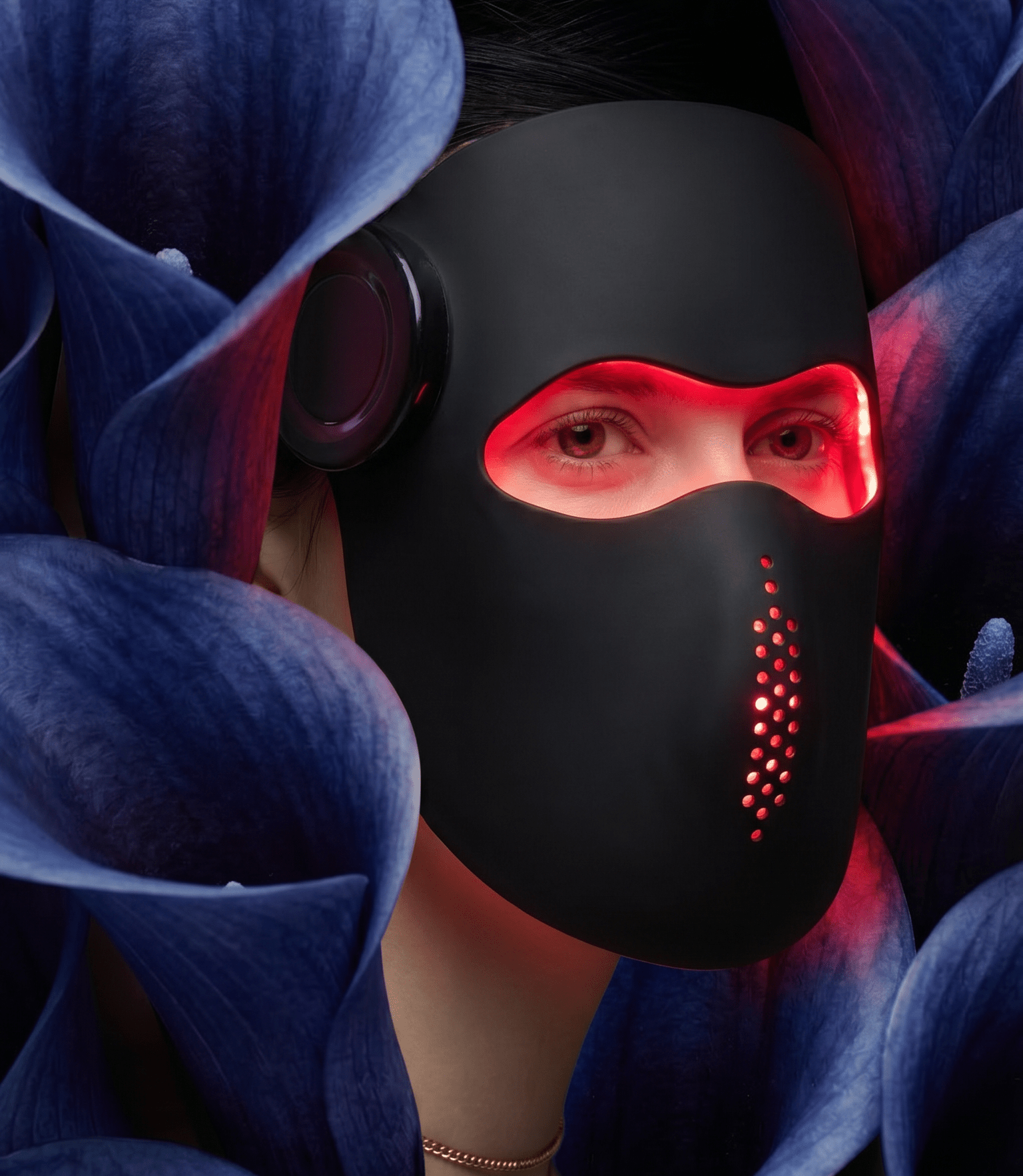 Person wearing a black mask with red lights surrounded by blue flowers