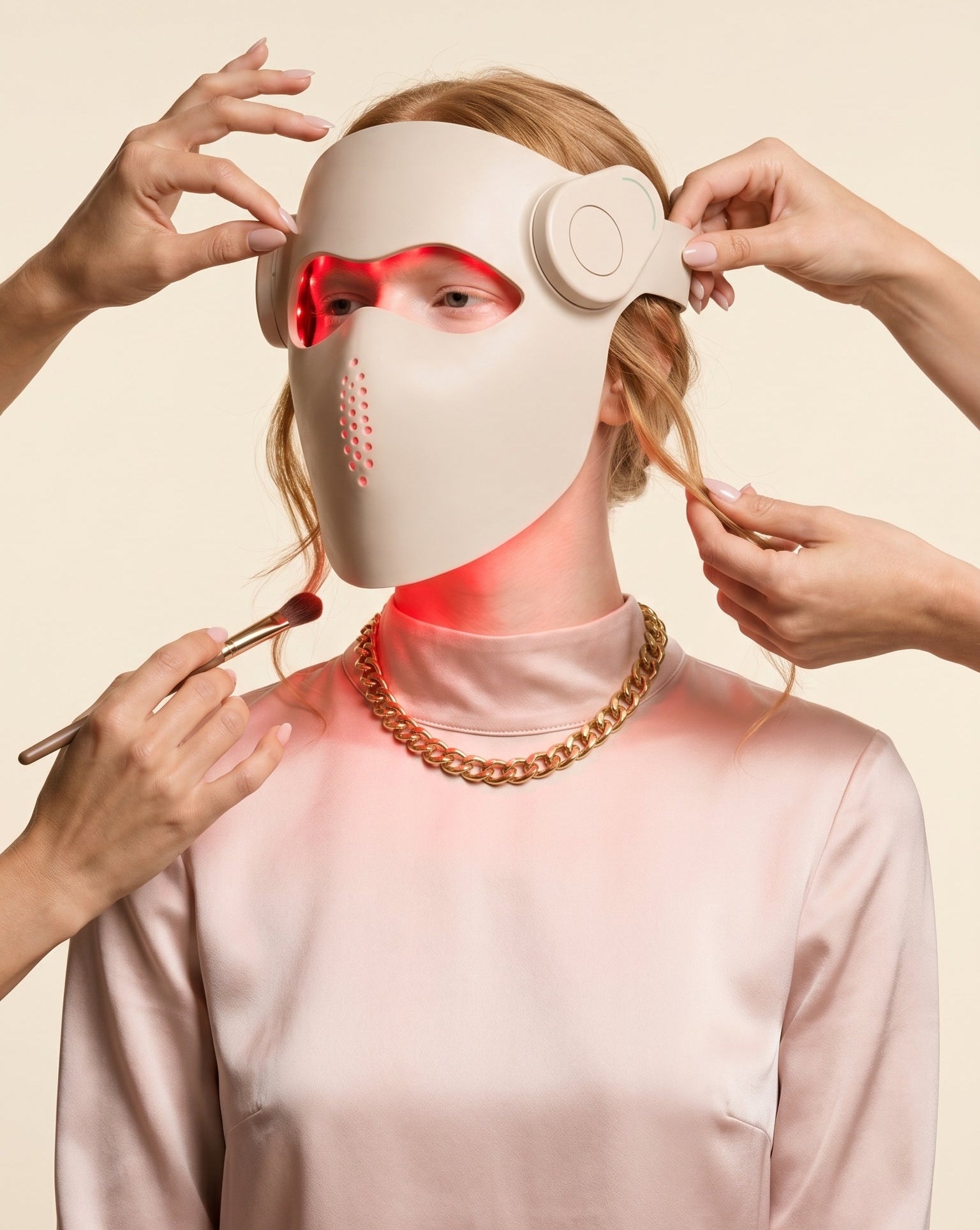 Person wearing a white face mask with red lights, held by two hands against a beige background