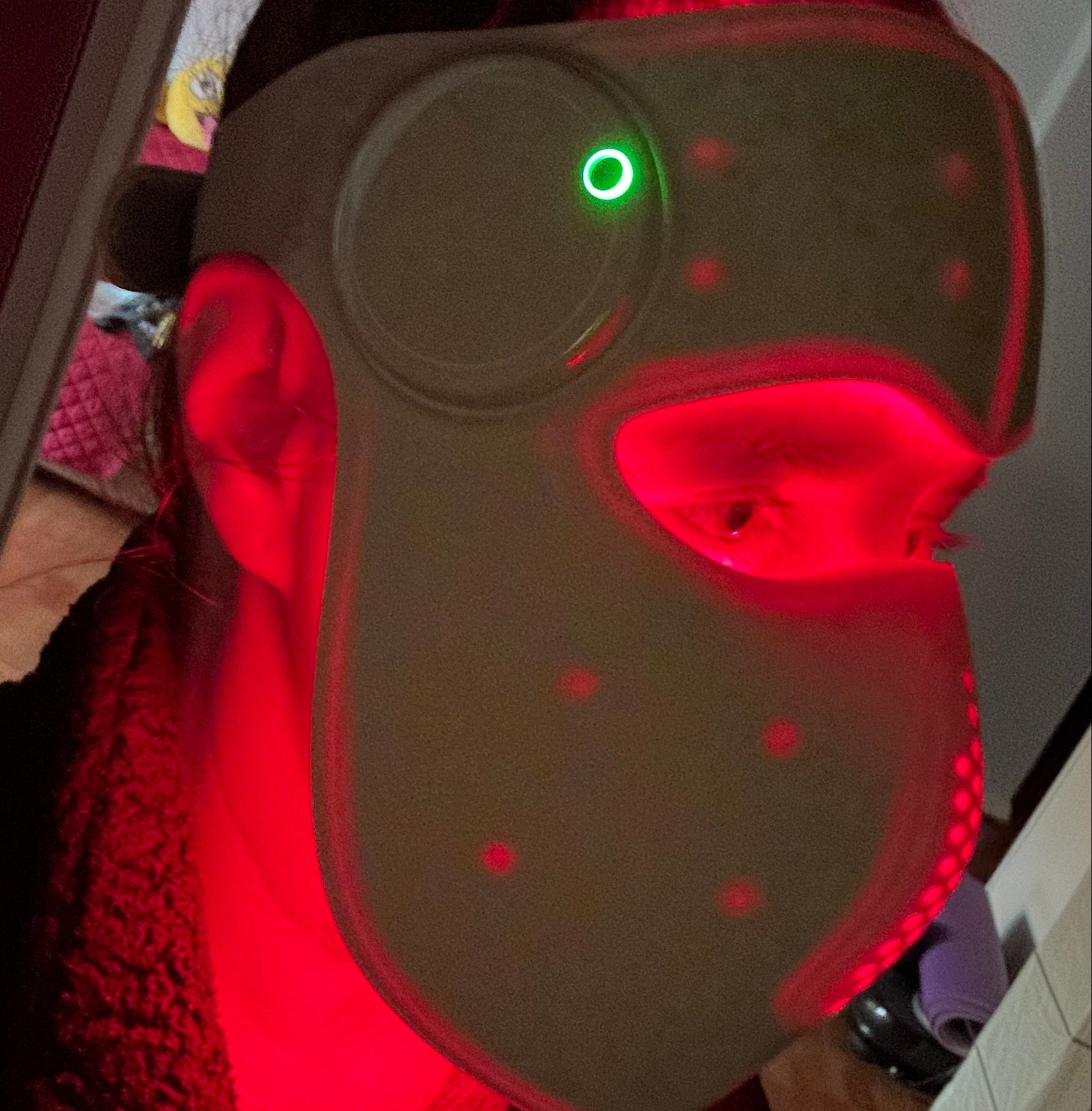 Person holding a red light device with a green light indicator.