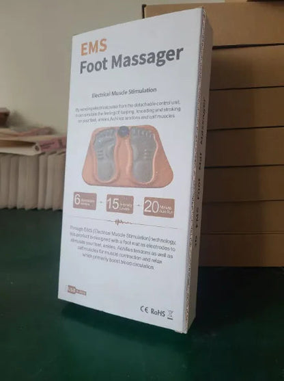 Box of an EMS Foot Massager on a green surface with a cardboard box in the background.