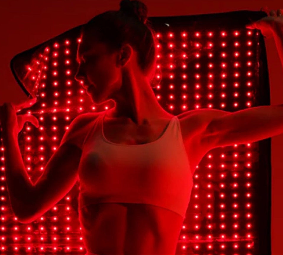 Person wearing a white tank top in front of a red LED panel
