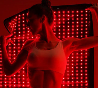 Person wearing a white tank top in front of a red LED panel