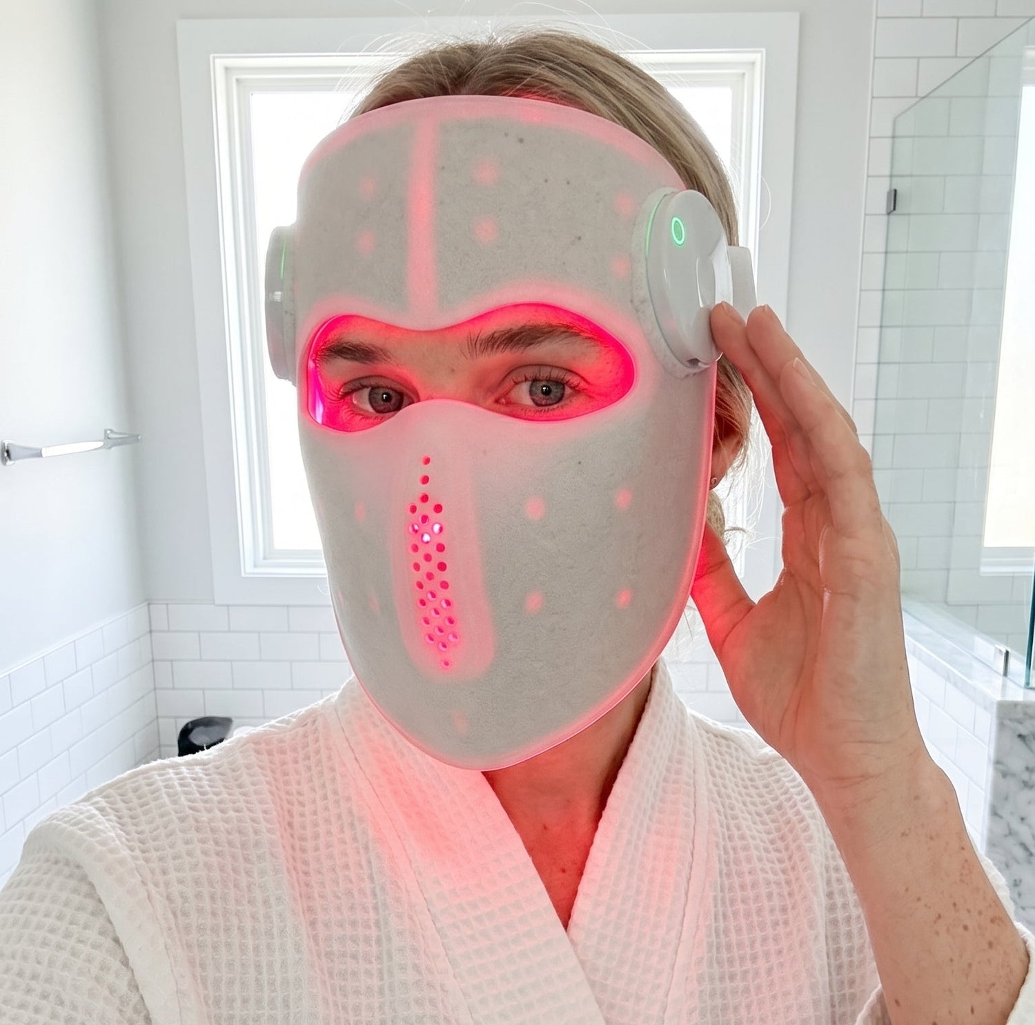 Person wearing a LED face mask in a bathroom setting