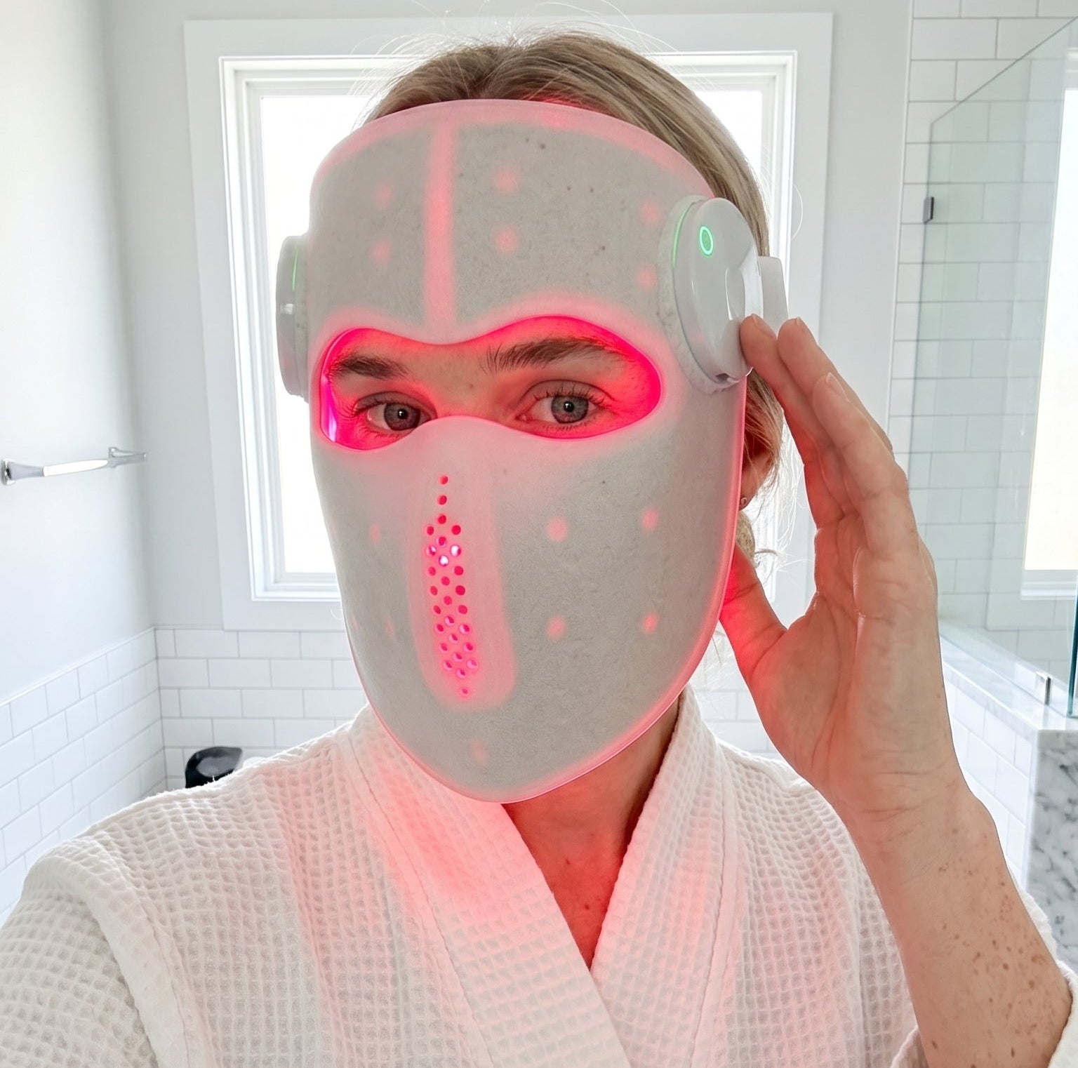 Person wearing a LED face mask in a bathroom setting