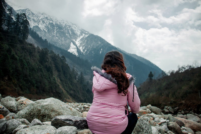 person-in-pink-looks-out-to-a-mountain-view