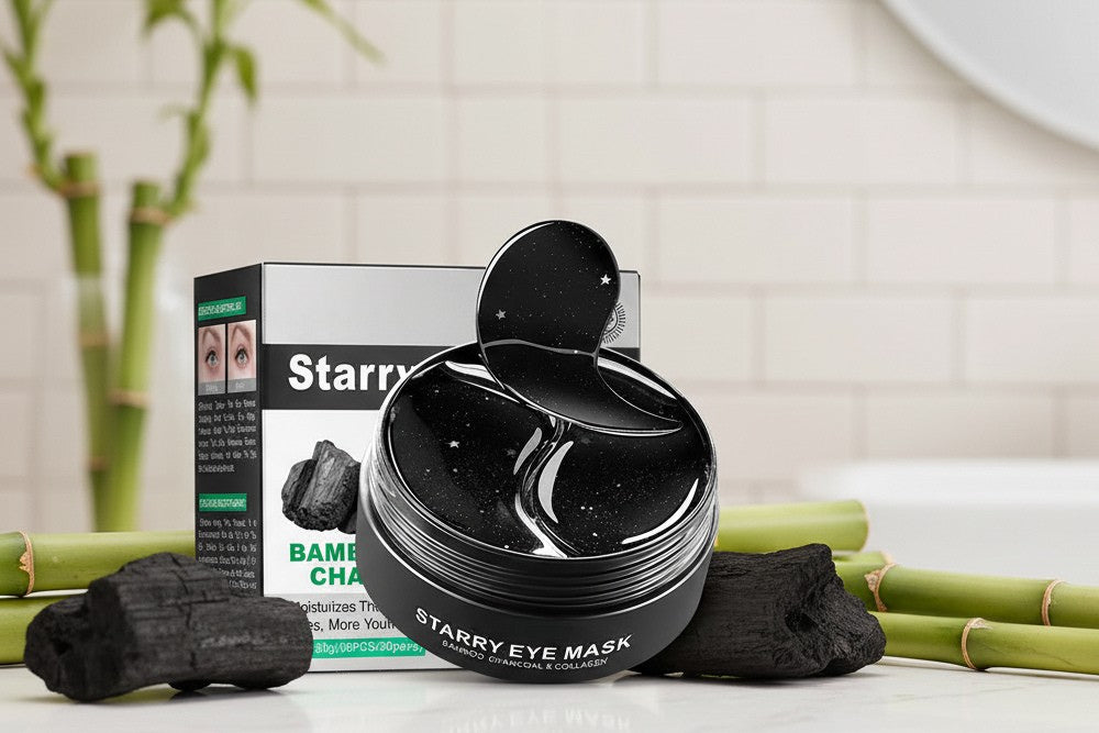 Black eye mask jar with packaging and charcoal on a white surface with bamboo sticks.