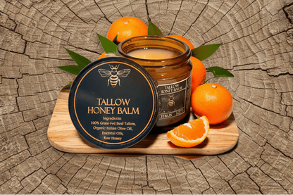 Tallow Honey Balm jar with beeswax lid on a wooden board with oranges and leaves.