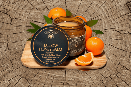 Tallow Honey Balm jar with beeswax lid on a wooden board with oranges and leaves.