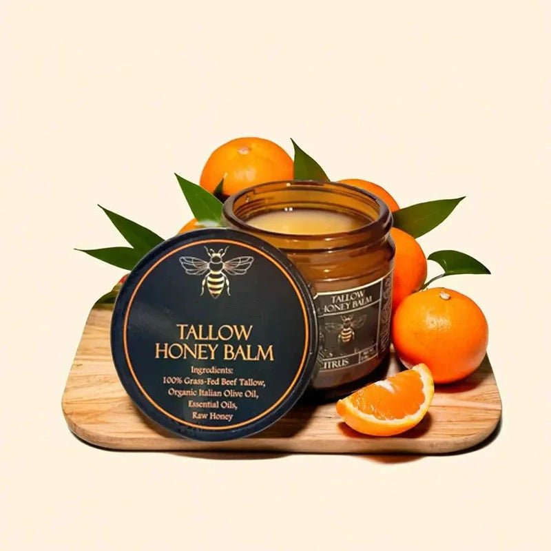 Tallow Honey Balm jar with beeswax lid on a wooden board with oranges and leaves.