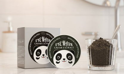 Eye masks with panda design on a white surface next to a container of caviar extract.