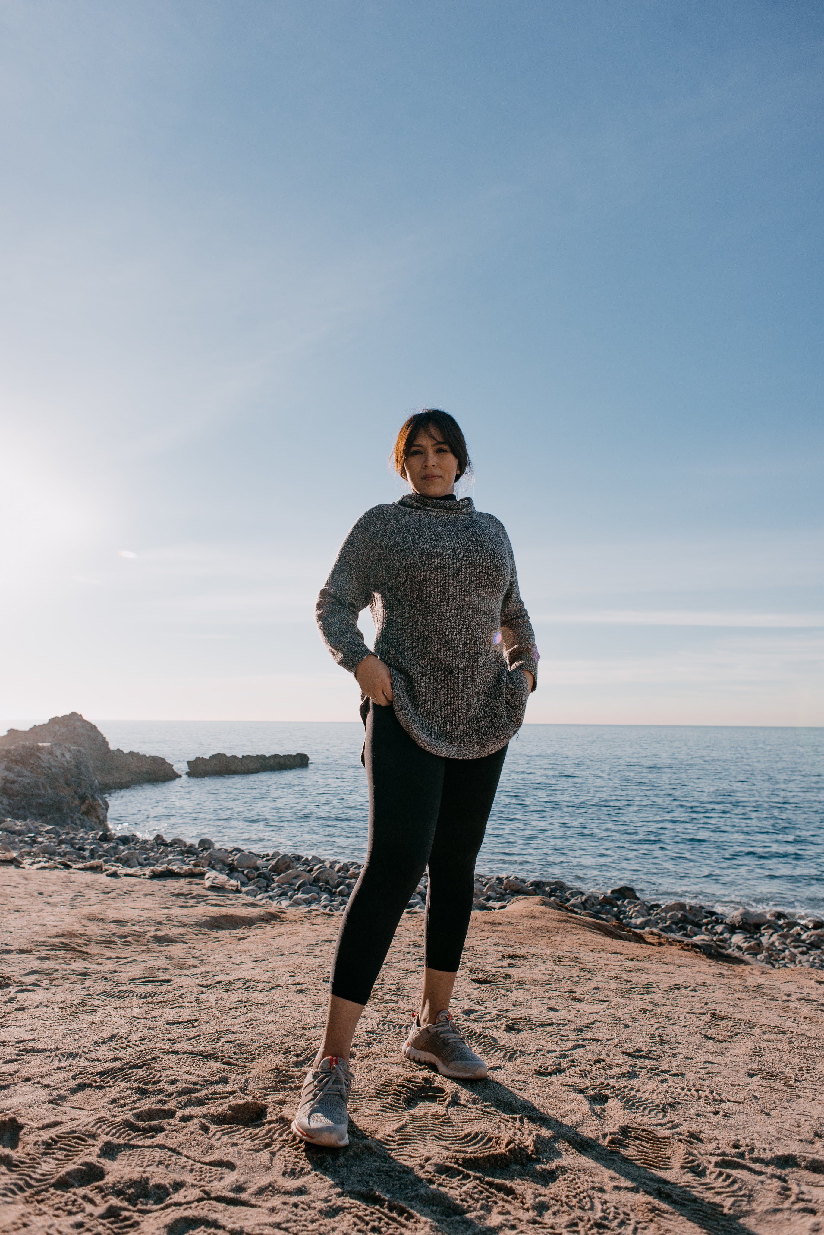 woman-in-sports-clothes-stands-on-a-beach-in-the-morning-light