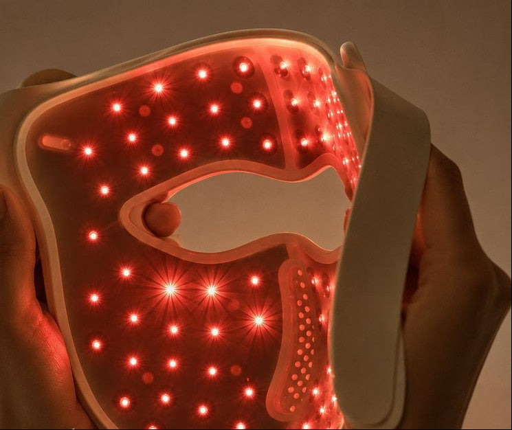 A person holds a NuYOU360 red light therapy face mask against their face, showing the illuminated LED lights. The image features promotional text highlighting the mask's precision LED technology.