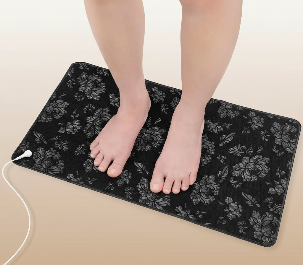 Person using a black floral-patterned grounding pad on a white background