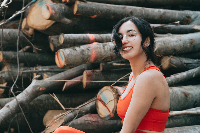 woman-smiles-at-the-camera-while-standing-wood-stack