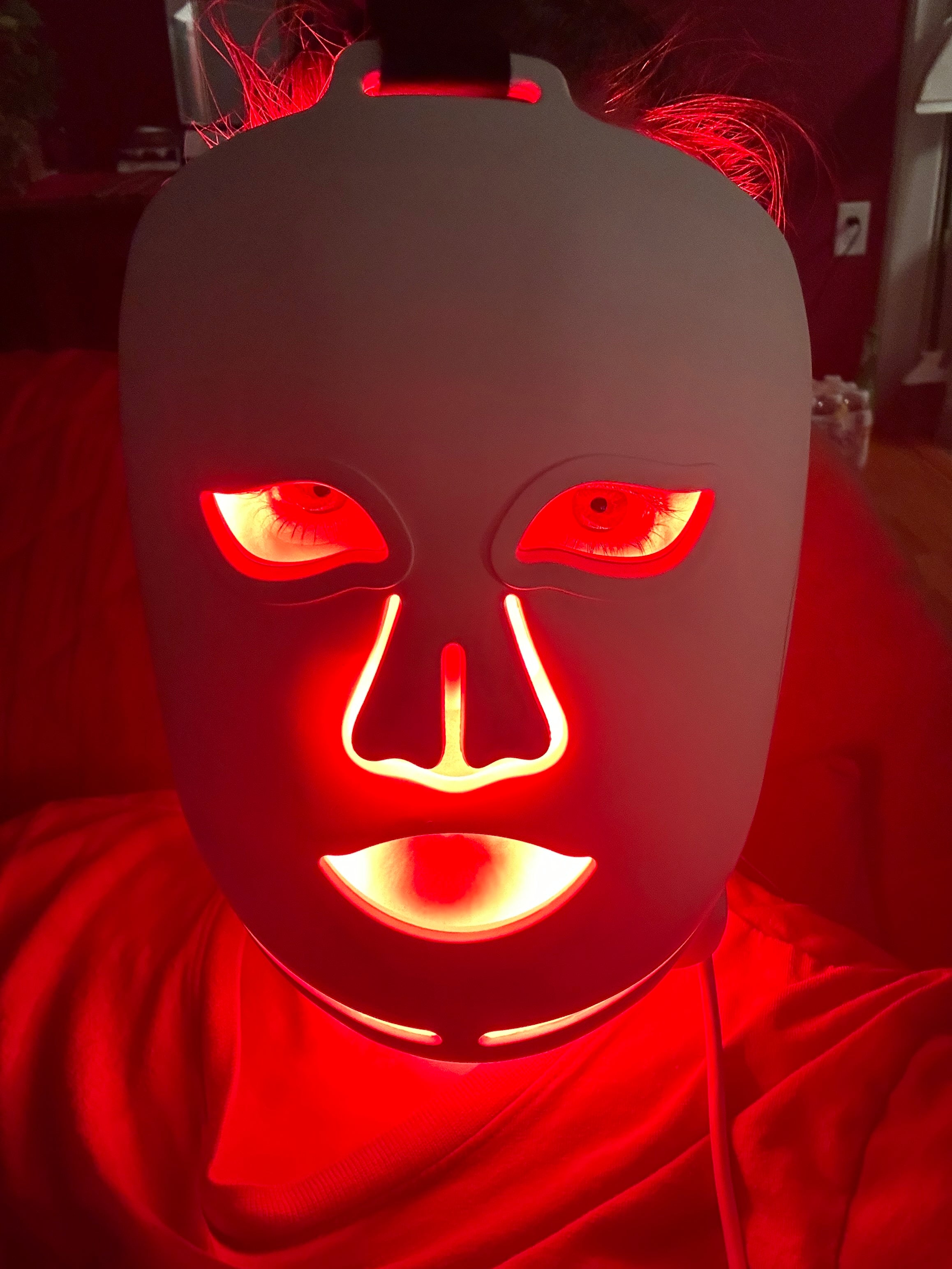 Mask with glowing red eyes and mouth against a red background