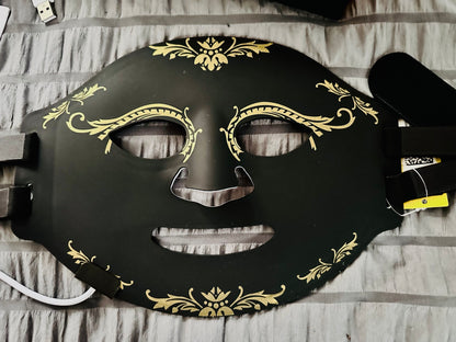 Black mask with gold decorative patterns on a striped fabric background