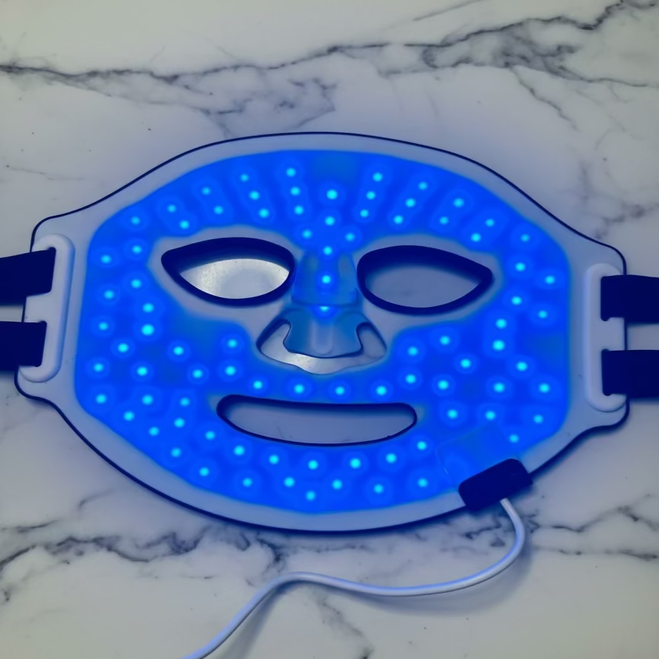 LED face mask with blue light on a white fabric background