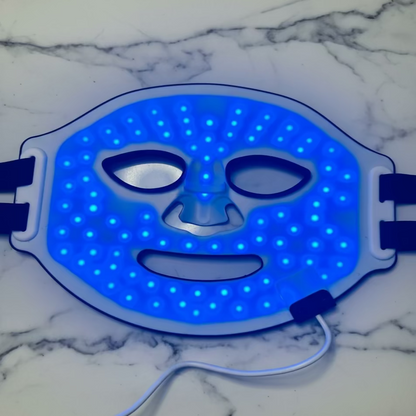 LED face mask with blue light on a white fabric background