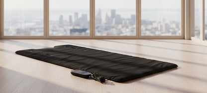 Black sauna blanket with a control panel on a white background
