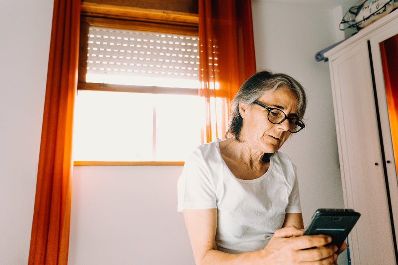 woman-looks-at-her-cell-phone-near-a-bright-window