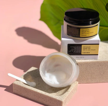 Cosrx skincare product with open jar and applicator on a pink background