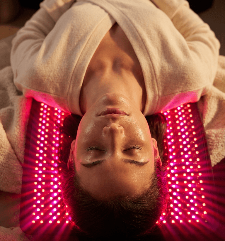Person receiving LED light therapy on their face with pink lights.