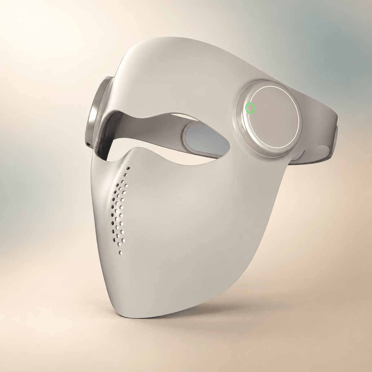 A white LED neck and face mask with a circular control panel on the side and a small green indicator light, shown on a soft beige background.